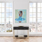 Print featuring black or african american ballerina in blue, aqua, white and gold tutu with soft green background with gold accents in hallway with black hallway table.